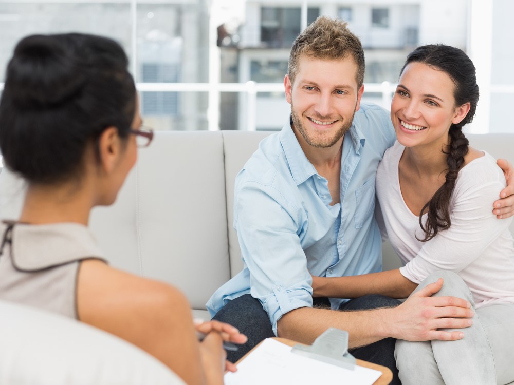 Smiling couple reconciling at therapy session in therapists office