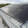 Modern suburban house with a standing seam metal roof and solar panels installed, eco-friendly energy-efficient home in Canada under clear blue sky.